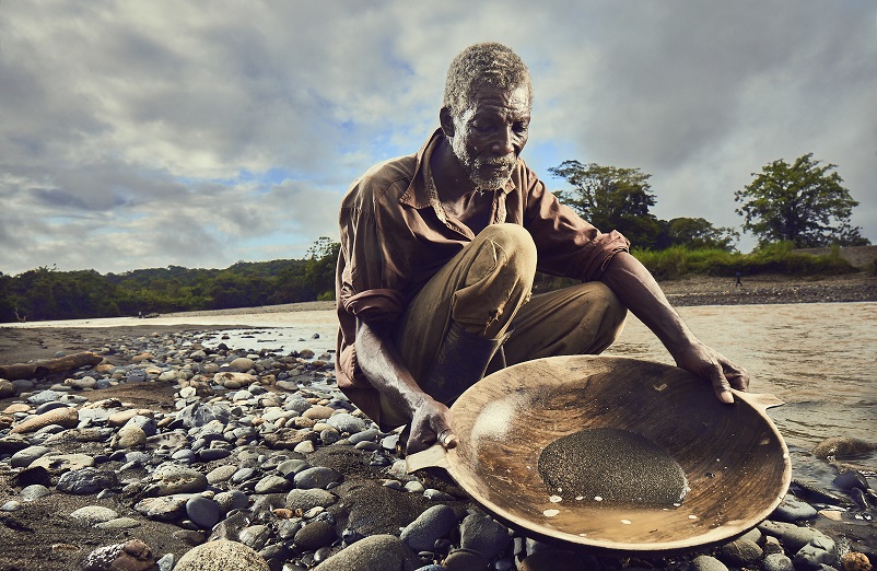 Minero de subsistencia (barequero) lavando oro con batea a orillas de un río del Chocó