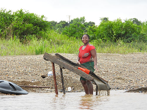 Mujer minera de subsistencia (barequera) del Chocó lavando oro con batea a orillas del río